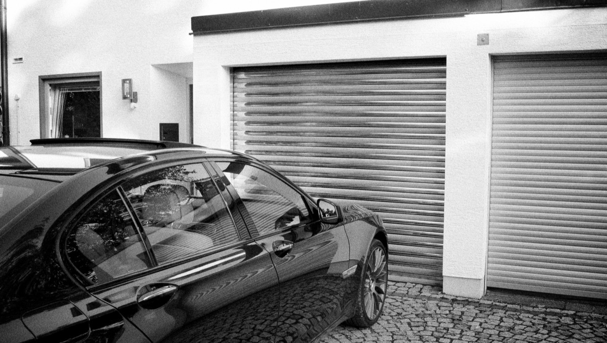 Car is parked in front of a garage with a security roller gate